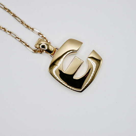 38 mm block letter pendant in 14K or 18K solid gold, shown held between fingers for scale