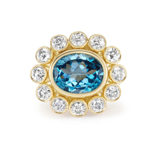 Gold ring with a blue gemstone and clear diamonds on a white background