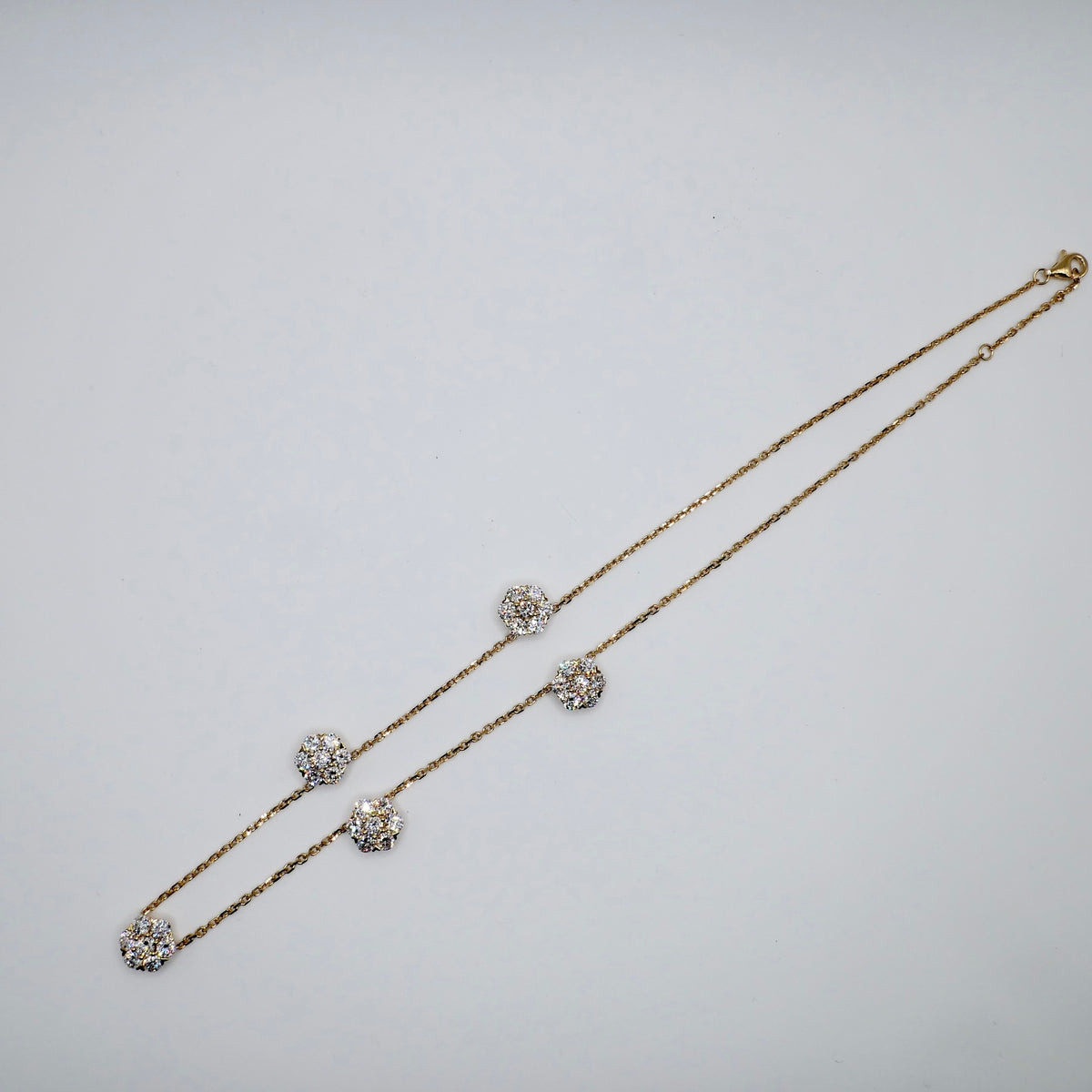 Lab diamond flower necklace with seven-stone clusters spaced along an 18K gold cable chain