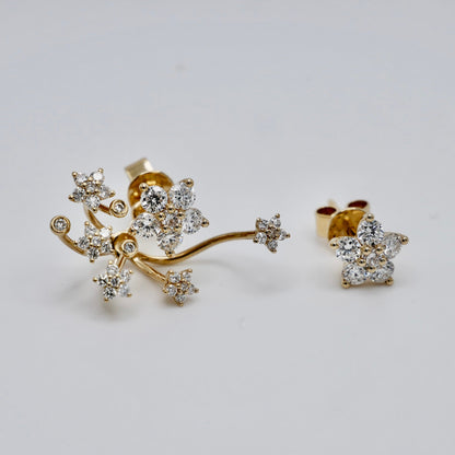 A pair of gold branch-shaped stud earrings with multiple starburst clusters of clear gemstones, displayed on a light gray background.
