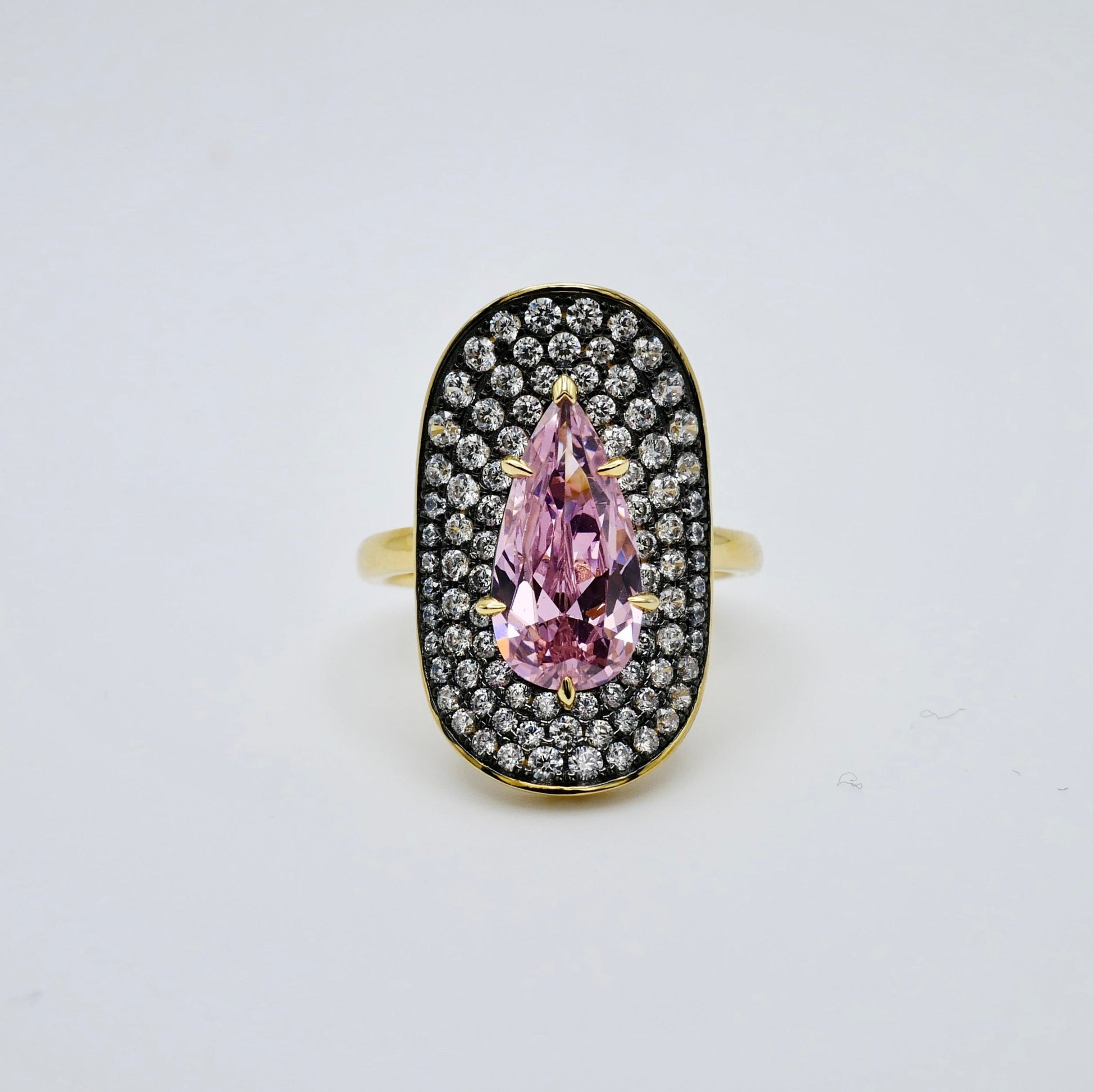 Ring with a pink teardrop-shaped gemstone and diamond accents on a light gray background