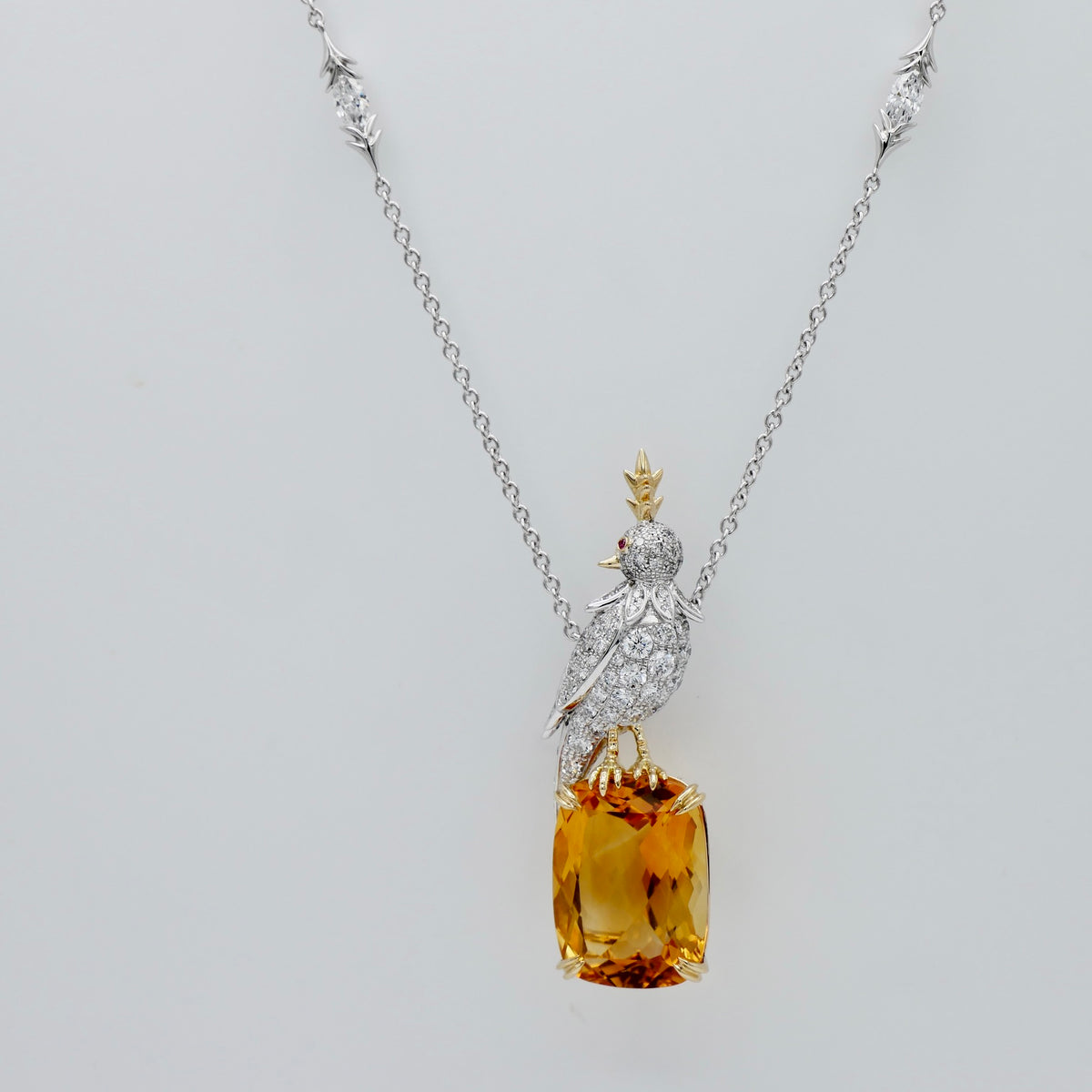 18 carat elongated cushion lab citrine held in 18K yellow gold claw prongs below a pavé bird