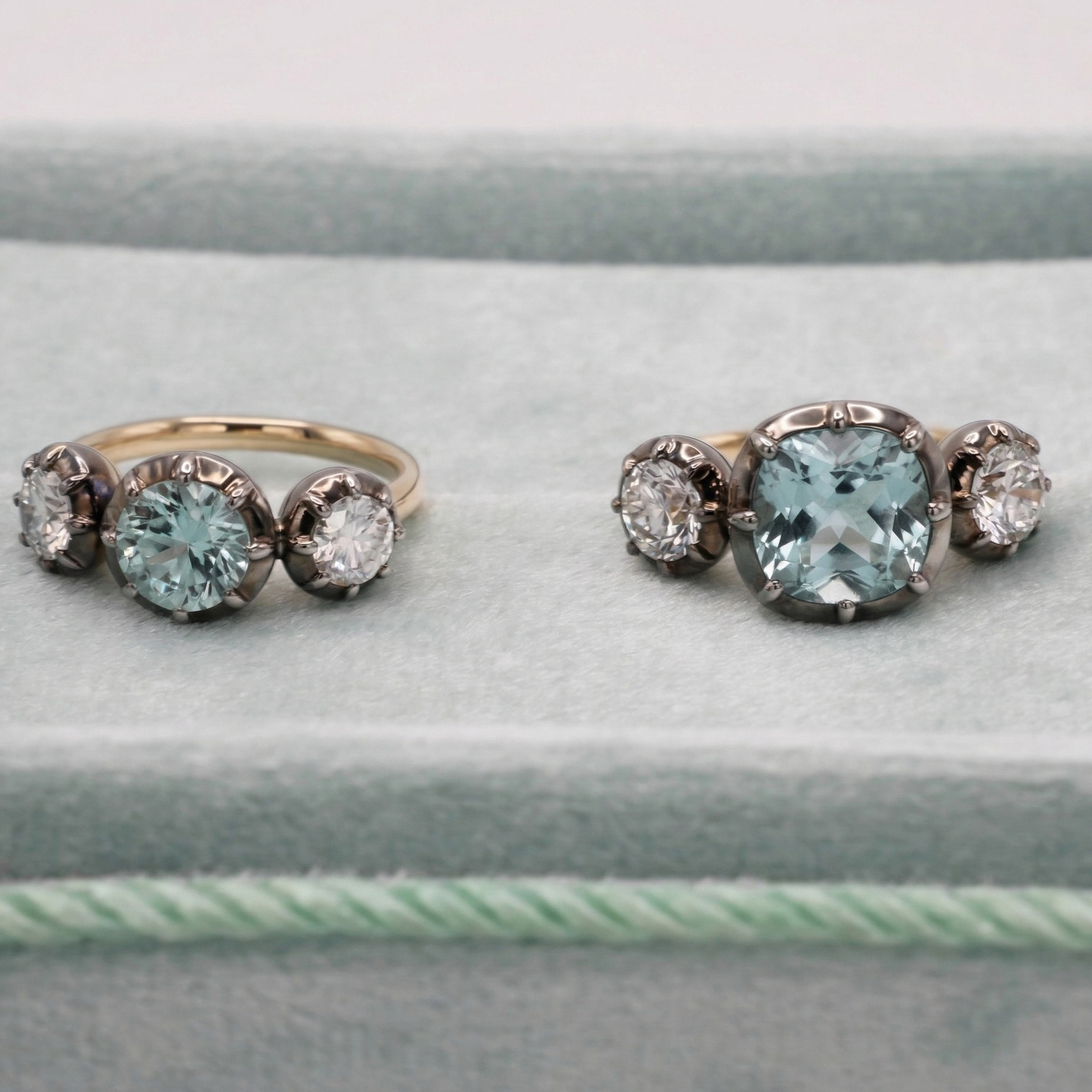 Two rings with aquamarine gemstones on a light gray surface