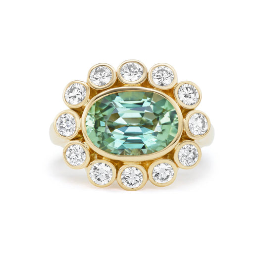Ring with a green gemstone and diamond-studded gold band on a white background