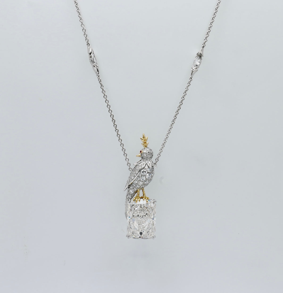 Platinum bird pendant pavé set with moissanites, perched on an 18 carat radiant cut lab grown diamond