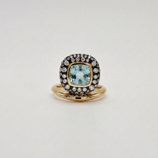 Gold ring with a blue gemstone and diamond accents on a light gray background